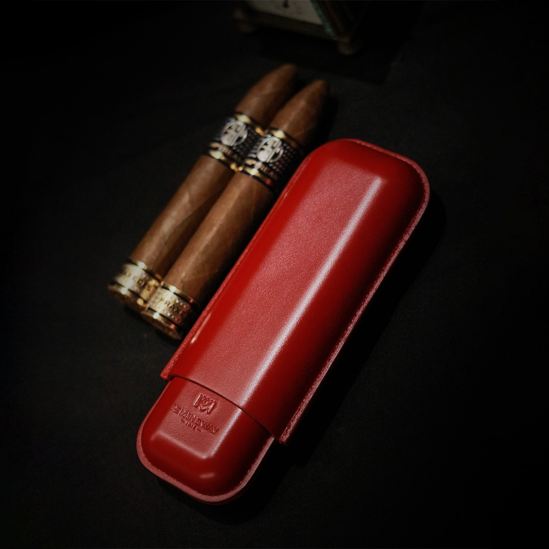 Hemingway Red leather cigar case with three cigars on a dark background